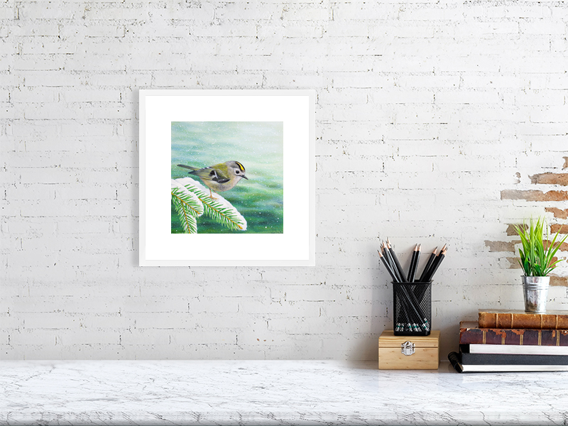 Goldcrest print in a white frame hanging on a wall.